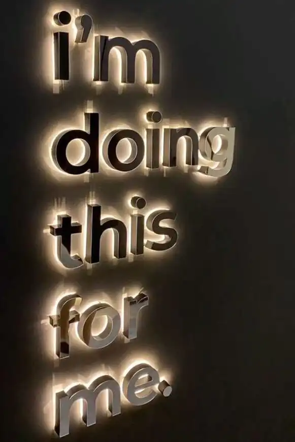 Illuminated quote on a dark wall saying, I'm doing this for me, emphasizing self-care and personal motivation.