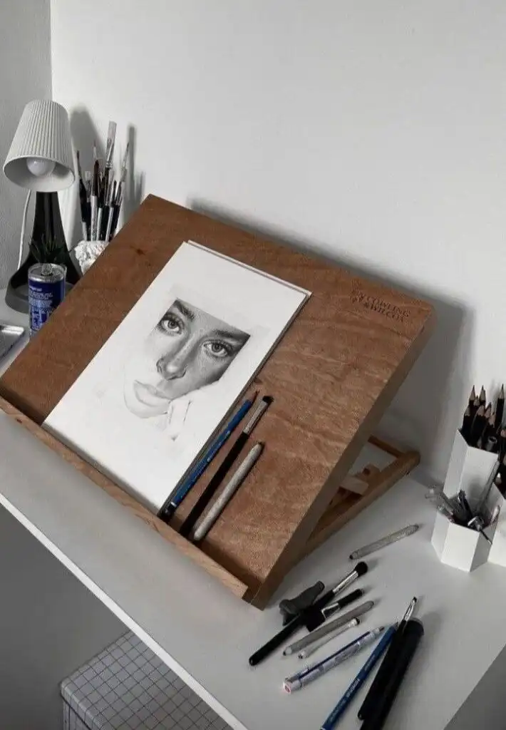 Drawing desk with portrait sketch, pencils, and markers, showcasing an artist's creative workspace setup.