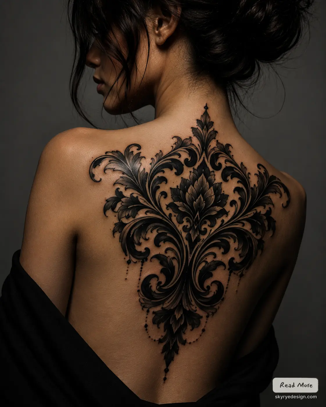 Ornate blackwork floral filigree back tattoo covering upper back and spine on a woman, elegant dark ornamental design