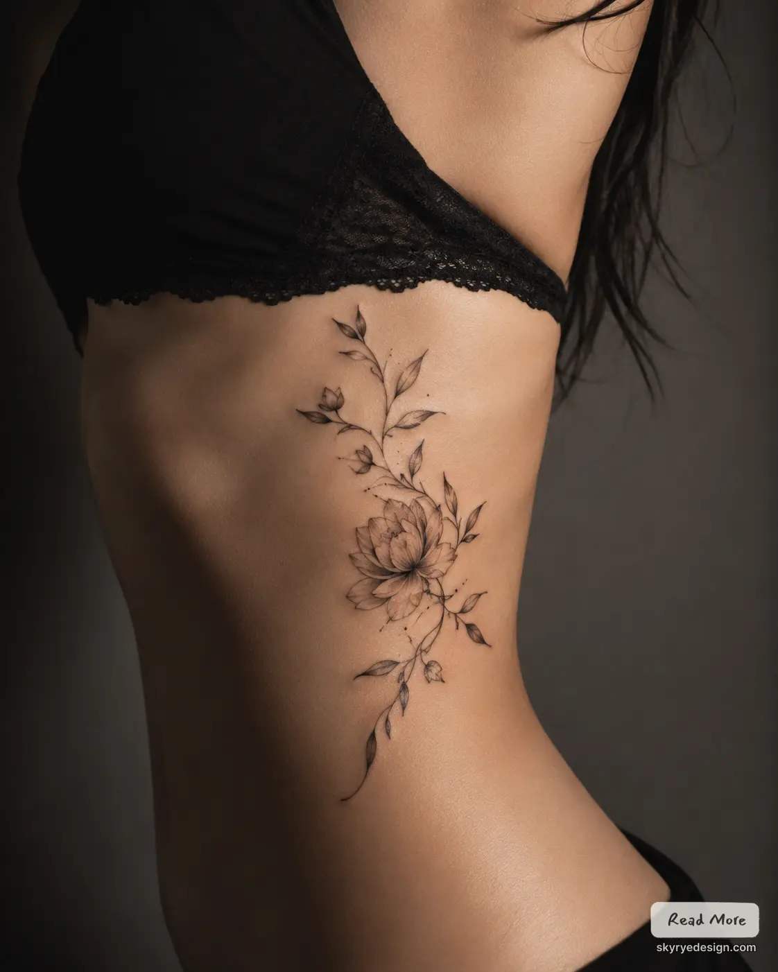 Delicate black-ink floral vine tattoo on woman's ribcage — minimalist botanical side piece beside a black lace bra