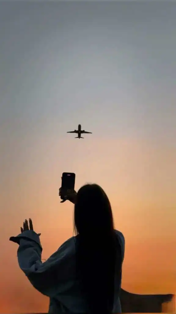 cdeadffe-5bb6-4e41-8348-7f7eba758568 Woman photographing a plane flying against a sunset sky. Capture the perfect travel moment with stunning aerial views. | Sky Rye Design Woman photographing a plane flying against a sunset sky. Capture the perfect travel moment with stunning aerial views.