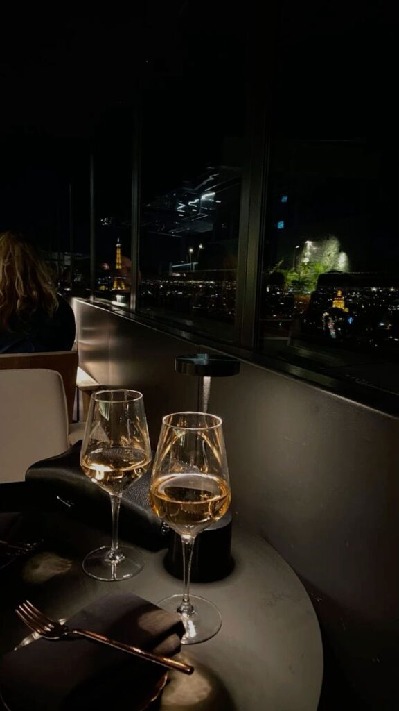 ceb663a9-2e25-4176-bf86-01ebe7dfaf65 Romantic dinner with champagne glasses overlooking city lights and iconic landmark at night. Luxurious dining ambiance. | Sky Rye Design Romantic dinner with champagne glasses overlooking city lights and iconic landmark at night. Luxurious dining ambiance.
