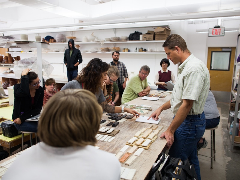 departments1 Group of people in a workshop discussing materials and designs on a table in a brightly lit studio. | Sky Rye Design Group of people in a workshop discussing materials and designs on a table in a brightly lit studio.