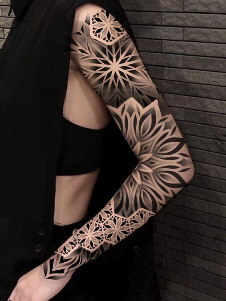 Ilustración sin título Stylish full sleeve tattoo with intricate geometric patterns on a person wearing a black sleeveless outfit. | Sky Rye Design Stylish full sleeve tattoo with intricate geometric patterns on a person wearing a black sleeveless outfit.