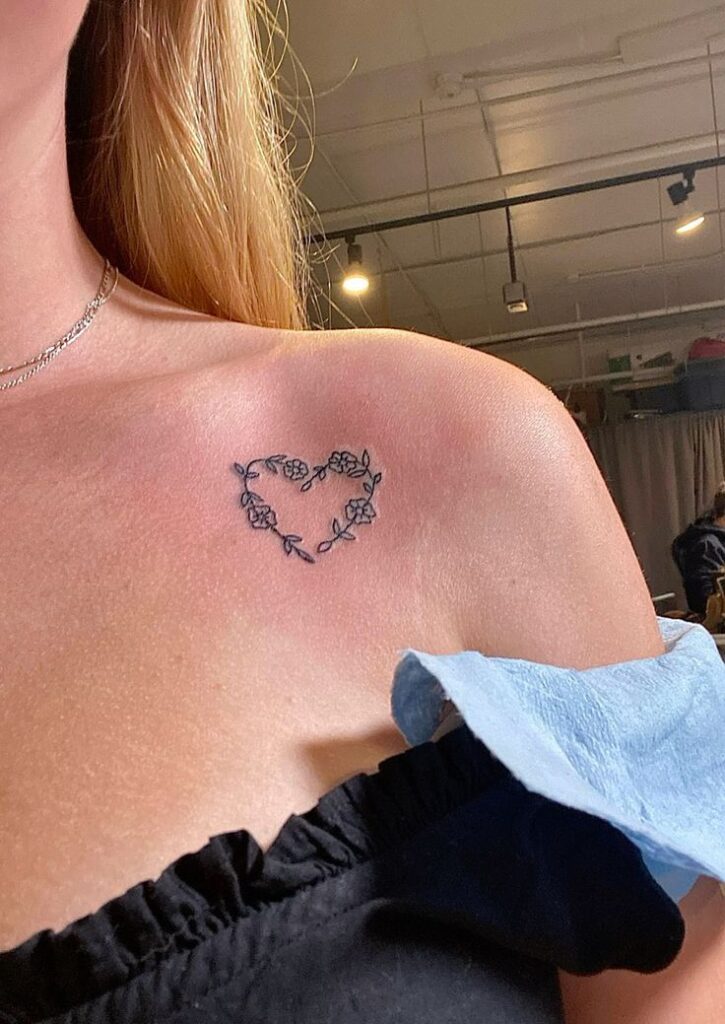 efced5d6-b961-460e-ae8c-9f8eb5e8ce7d Delicate floral heart tattoo on a woman's shoulder, symbolizing love and elegance, in a modern studio setting. | Sky Rye Design Delicate floral heart tattoo on a woman's shoulder, symbolizing love and elegance, in a modern studio setting.