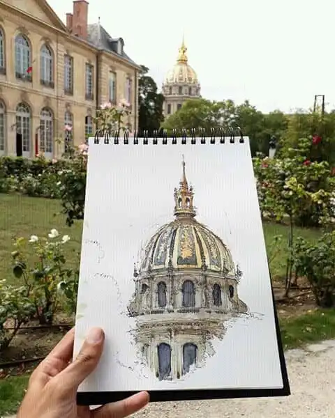 Sketch of a historic dome on a notepad, held in a garden setting with the real structure in the background.