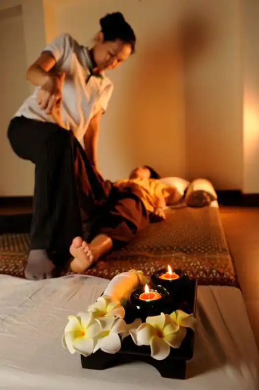 Thai massage therapy session with relaxation in a cozy spa setting, featuring candles and flowers for ambiance.