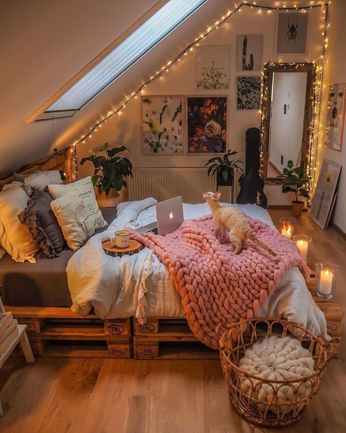 home decration ideas free project Cozy attic bedroom with string lights, a cat on a pink knitted blanket, laptop on bed, and warm decor for a relaxing ambiance. | Sky Rye Design Cozy attic bedroom with string lights, a cat on a pink knitted blanket, laptop on bed, and warm decor for a relaxing ambiance.