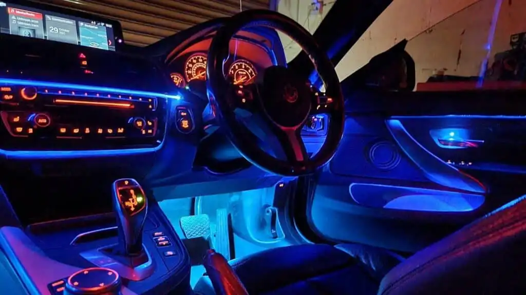 Luxury car interior with ambient blue lighting, illuminated dashboard, and modern steering wheel. Futuristic driving experience.