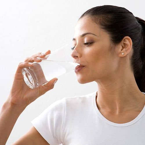 http___meo-lamdep_com_viec-can-lam-truoc-bua-trua-de-giup-giam-can-nhanh_ Woman drinking a glass of water, promoting hydration and healthy lifestyle, wearing a white shirt in a bright setting. | Sky Rye Design Woman drinking a glass of water, promoting hydration and healthy lifestyle, wearing a white shirt in a bright setting.