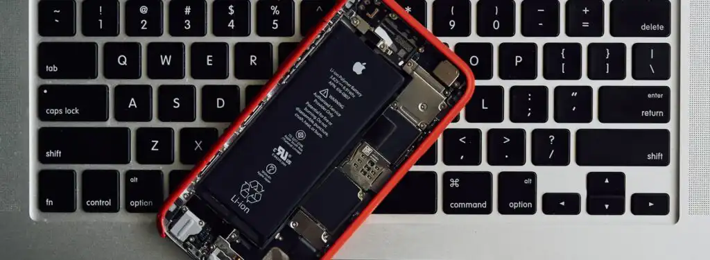 Open smartphone showing internal components, placed on a laptop keyboard, highlighting technology and repair.