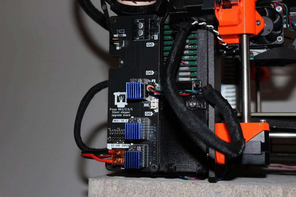 image Close-up of a Prusa MK2/2.5/S 3D printer's silent stepper upgrade board, showcasing wired components and cooling heatsinks. | Sky Rye Design Close-up of a Prusa MK2/2.5/S 3D printer's silent stepper upgrade board, showcasing wired components and cooling heatsinks.