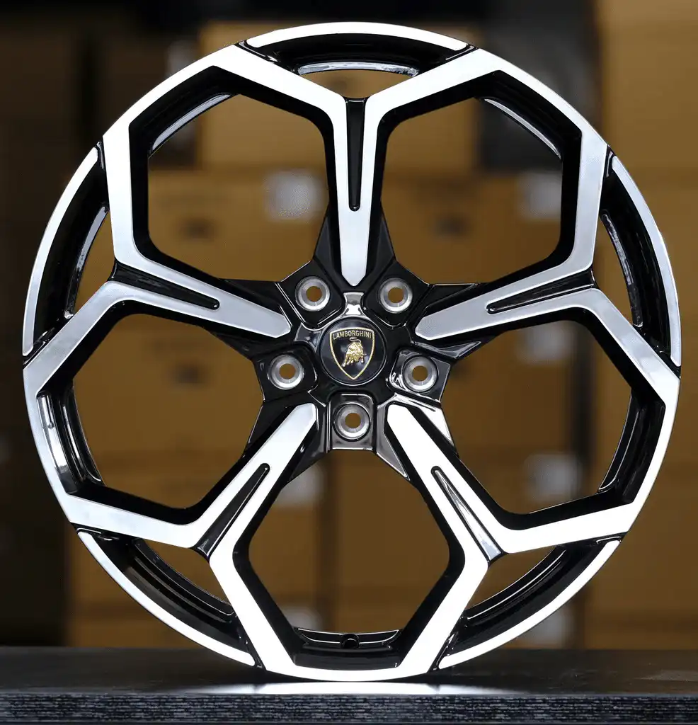 Close-up of a shiny Lamborghini wheel rim with a black and silver design in a showroom setting.