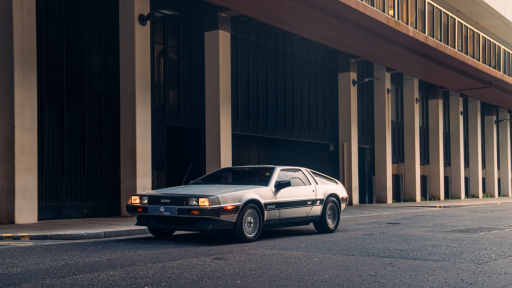 Silver DeLorean DMC-12 parked in an urban setting, showcasing classic retro automotive design and style.