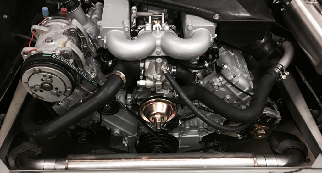 Close-up of a car engine with visible components including belts, hoses, and metal parts, showcasing intricate mechanical details.