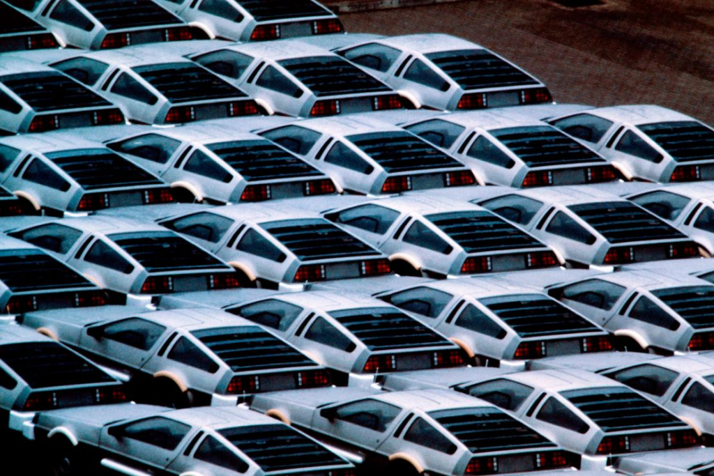 Stacked silver sports cars in parking lot, featuring iconic gullwing doors.