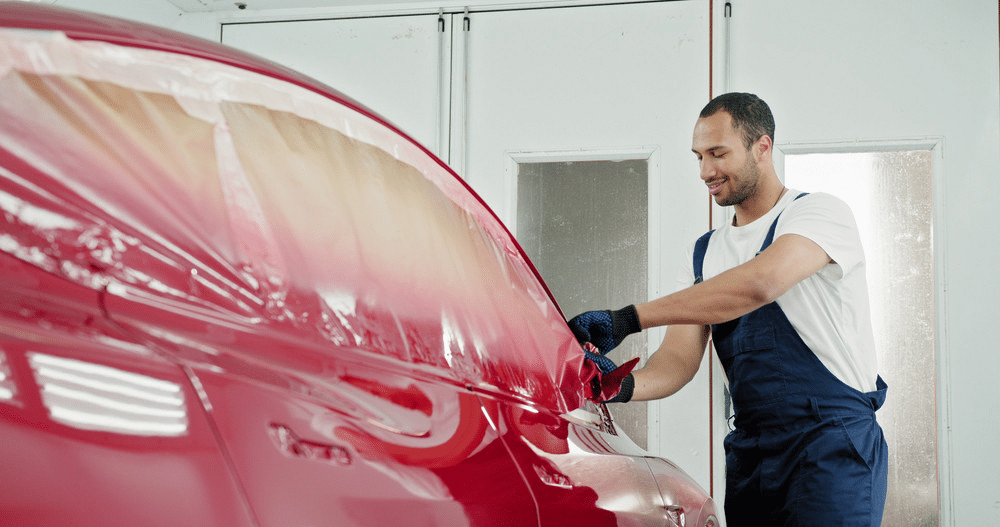 image Man in blue overalls polishing a red car in a workshop, focusing on smooth and shiny finish for car detailing and maintenance. | Sky Rye Design Man in blue overalls polishing a red car in a workshop, focusing on smooth and shiny finish for car detailing and maintenance.