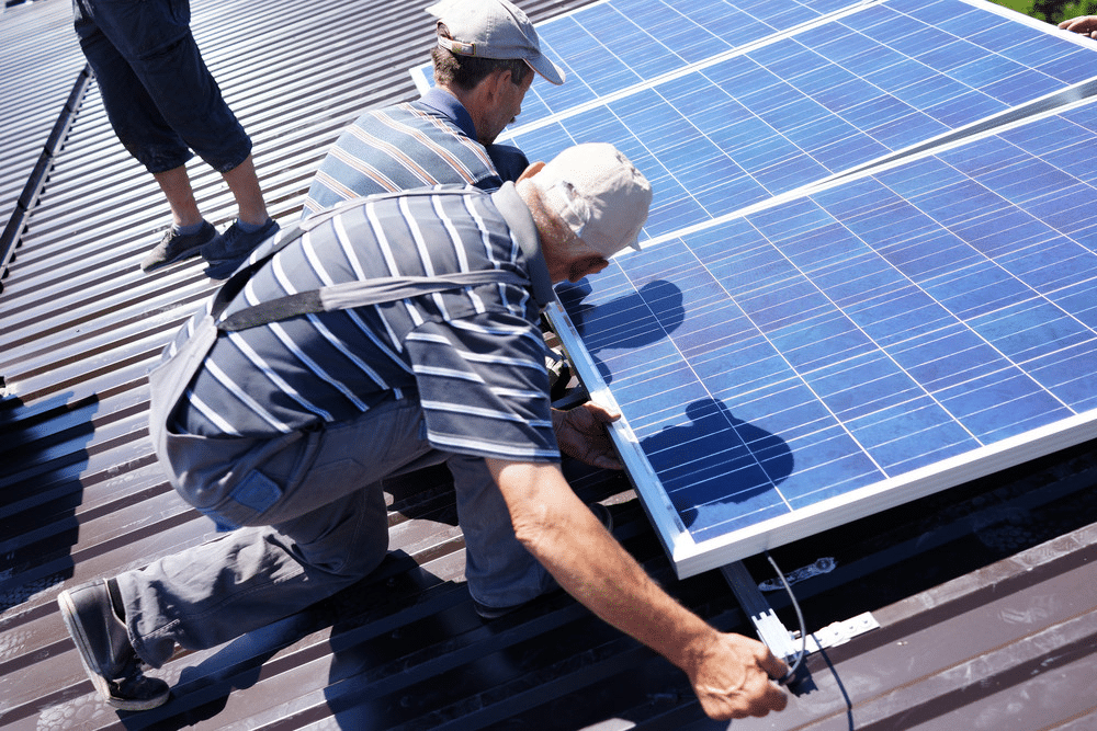 image Technicians installing solar panels on a metal rooftop, harnessing renewable energy for sustainable power solutions. | Sky Rye Design Technicians installing solar panels on a metal rooftop, harnessing renewable energy for sustainable power solutions.