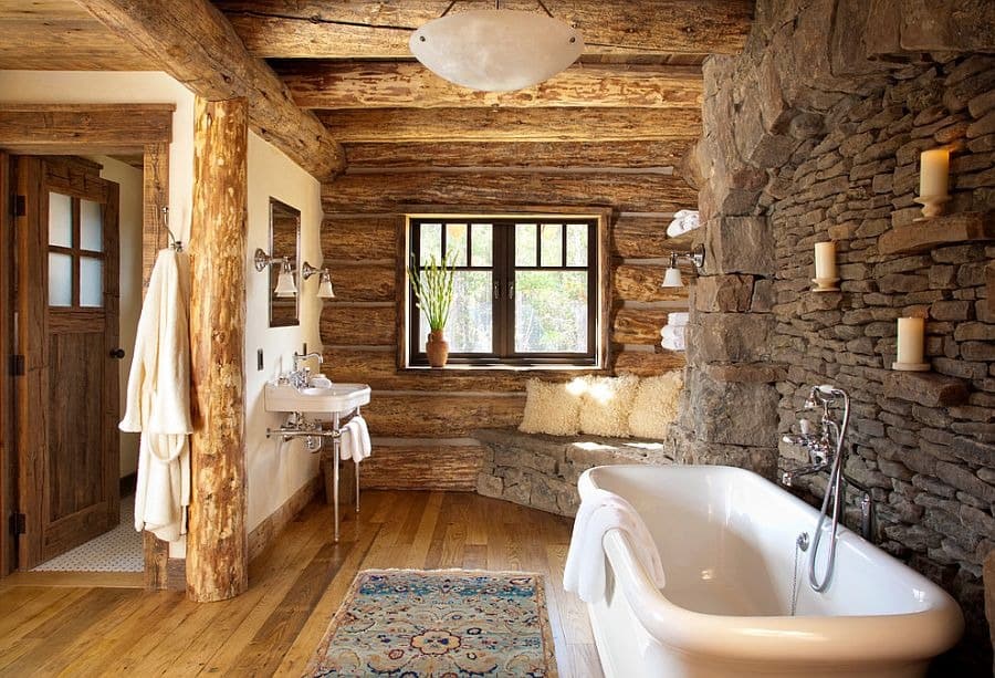 Rustic log cabin bathroom with stone walls, freestanding bathtub, candles, and wooden accents, creating a cozy, natural