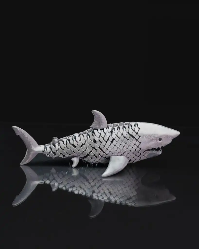 Realistic shark sculpture with a scaly texture on a reflective surface, set against a dark background, resembling sea