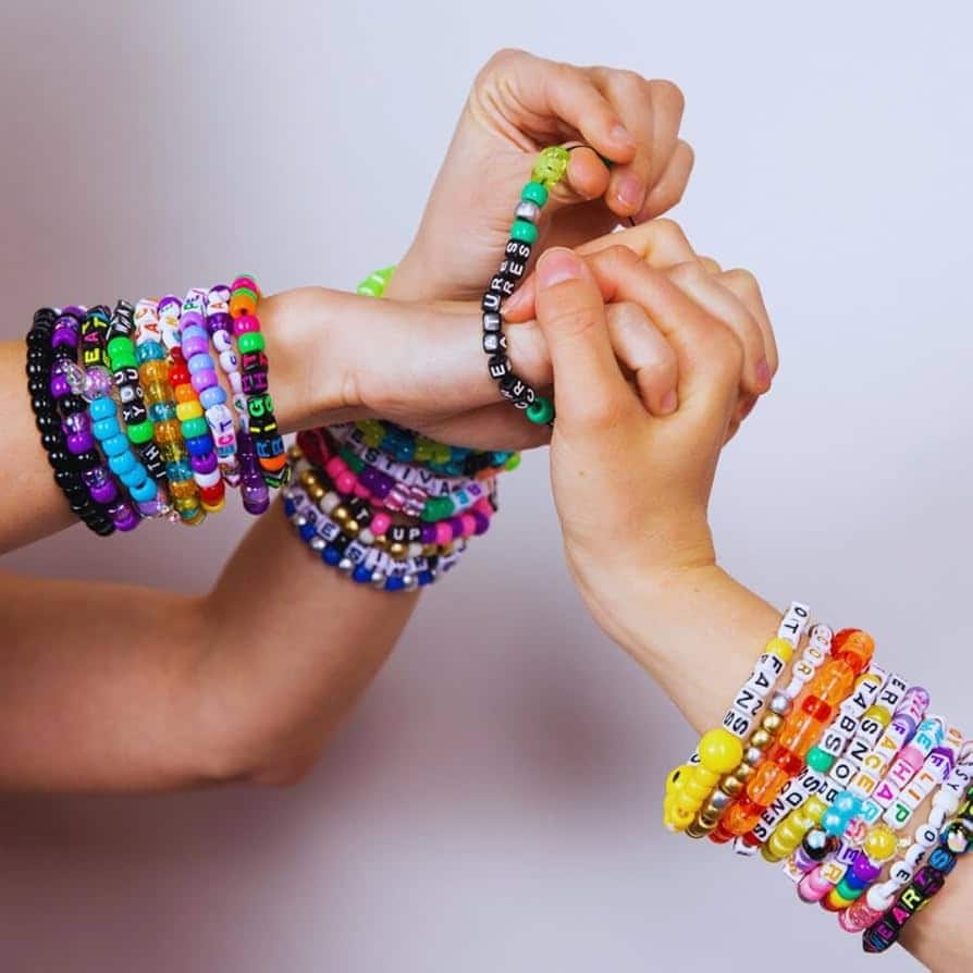 image Colorful beaded bracelets with words adorn two hands, showcasing vibrant DIY jewelry and creativity against a plain | Sky Rye Design Colorful beaded bracelets with words adorn two hands, showcasing vibrant DIY jewelry and creativity against a plain