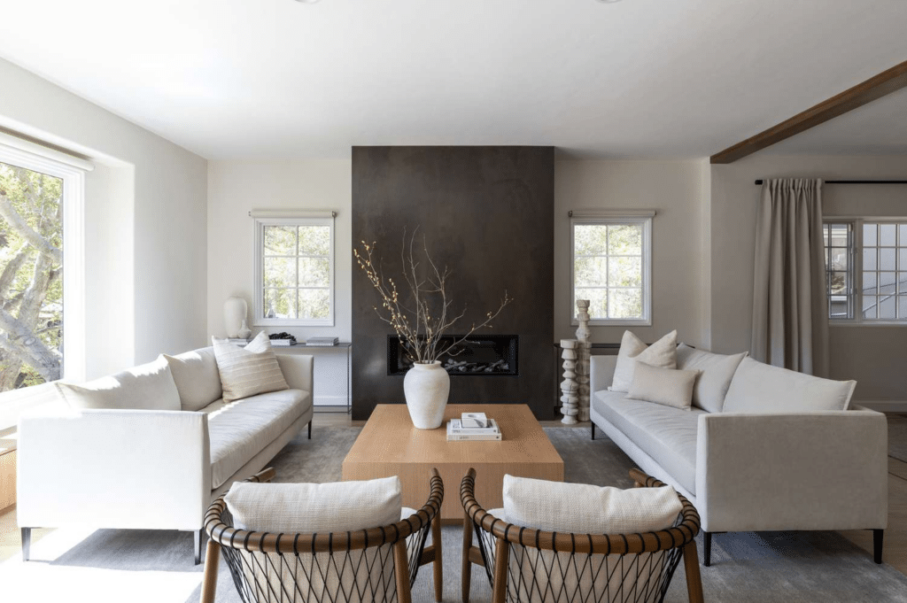 Modern living room with neutral sofas, black fireplace, and wooden coffee table, accented by natural light and minimalist