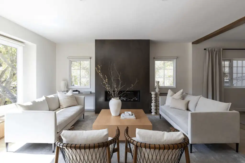 Modern living room with neutral sofas, black fireplace, and wooden coffee table, accented by natural light and minimalist