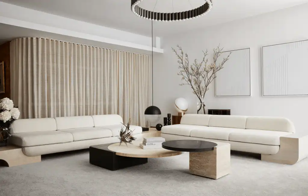 Modern living room with beige sofas, round coffee tables, large wall art, and contemporary lighting, creating a stylish,