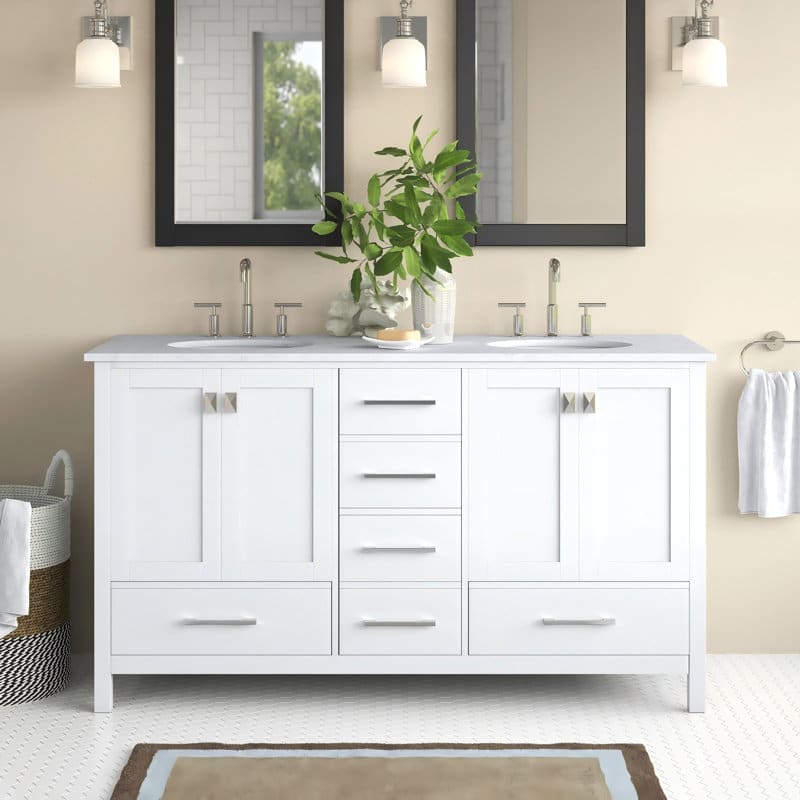White double-sink bathroom vanity with marble countertop, chrome faucets, black framed mirrors, wall sconces and decorative green plant.