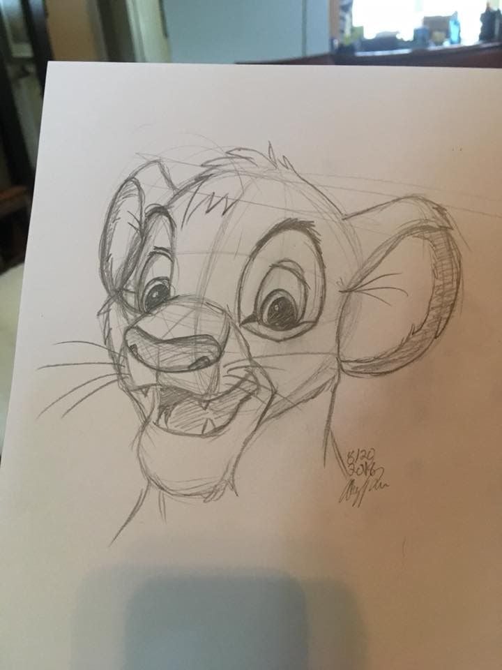Pencil sketch of a lion cub character with a happy expression, drawn on white paper with detailed facial features.