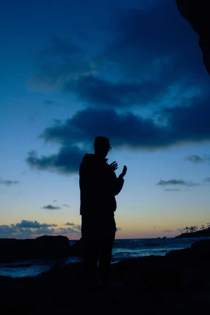 man making dua at blue hour Silhouette of a person by the sea at dusk, with a stunning blue and orange sunset sky in the background. | Sky Rye Design Silhouette of a person by the sea at dusk, with a stunning blue and orange sunset sky in the background.