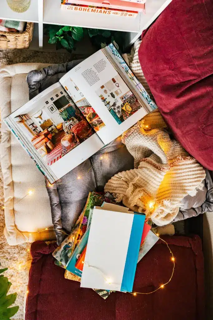 moonstone+kitchen+cozy+bohemian+reading+nook+Haley+Post Cozy reading nook with colorful books and fairy lights, featuring an open interior design magazine on a cushion. | Sky Rye Design Cozy reading nook with colorful books and fairy lights, featuring an open interior design magazine on a cushion.