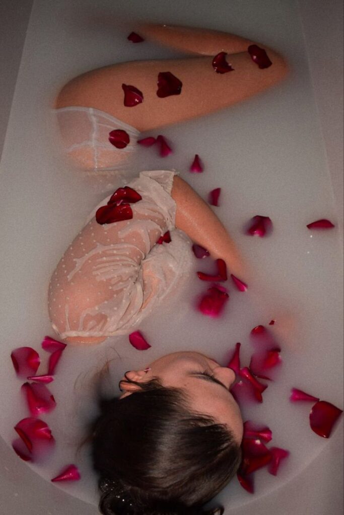 photo _ mxc Woman in a sheer dress relaxes in a milky bath, surrounded by red rose petals, creating a serene and romantic atmosphere. | Sky Rye Design Woman in a sheer dress relaxes in a milky bath, surrounded by red rose petals, creating a serene and romantic atmosphere.