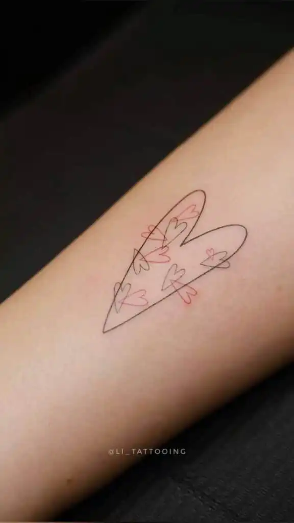 Minimalist heart tattoo design with layered outlines in black and red ink on arm. Simple and elegant body art concept.