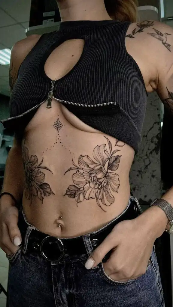 ✔✔✔✔✔✔✔✔ Floral tattoos on torso with crop top and jeans, showcasing detailed flower art and belly button piercing. Fashion and body art expression. | Sky Rye Design Floral tattoos on torso with crop top and jeans, showcasing detailed flower art and belly button piercing. Fashion and body art expression.