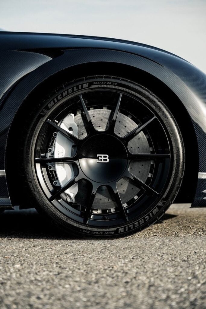 Bugatti wheel close-up: black alloy rim, Michelin tire, white brake caliper and carbon-fiber fender
