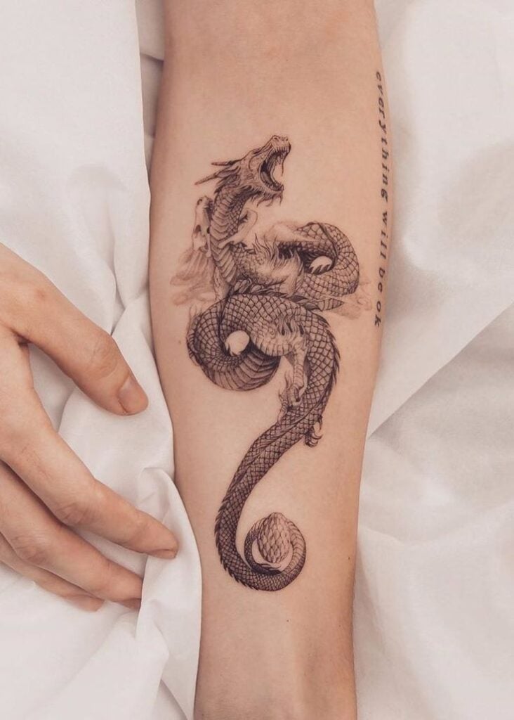 Black ink dragon tattoo coiled on inner forearm with intricate scales and open-mouthed head