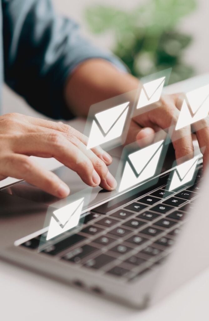 Email marketing concept: hands typing on laptop with floating email icons for inbox management and outreach. Treat Email