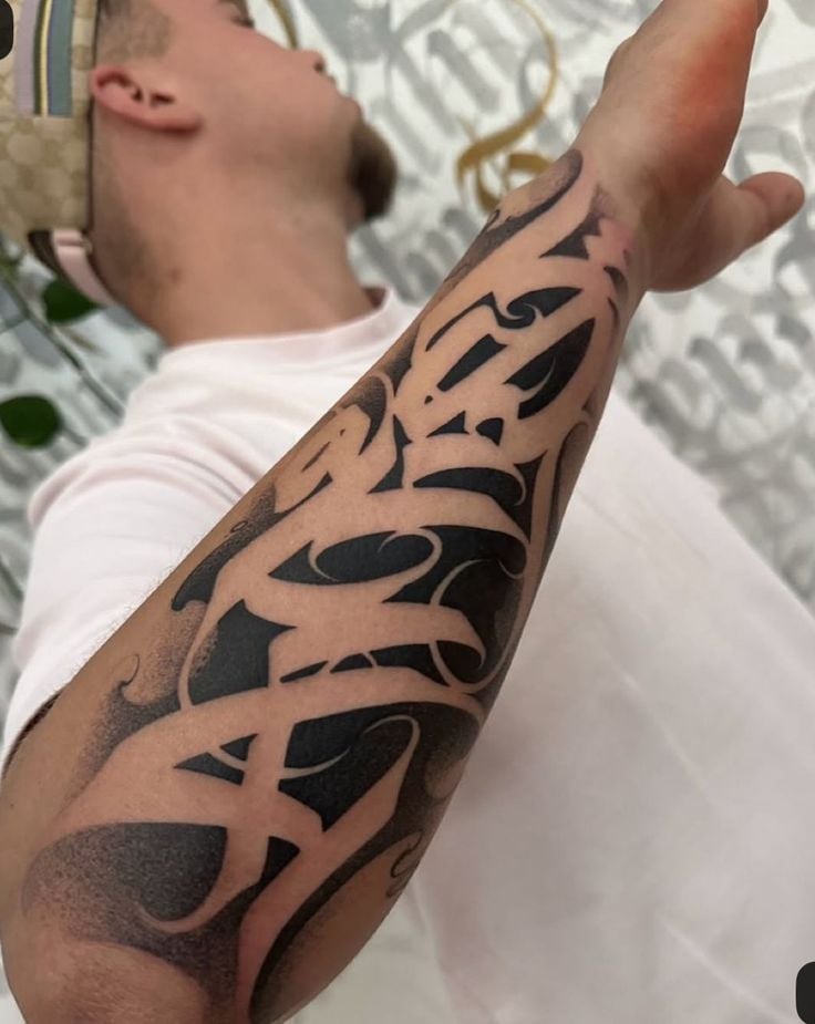Close-up of bold blackwork tribal forearm tattoo on a man's arm, abstract Polynesian-style sleeve with negative-space swirls