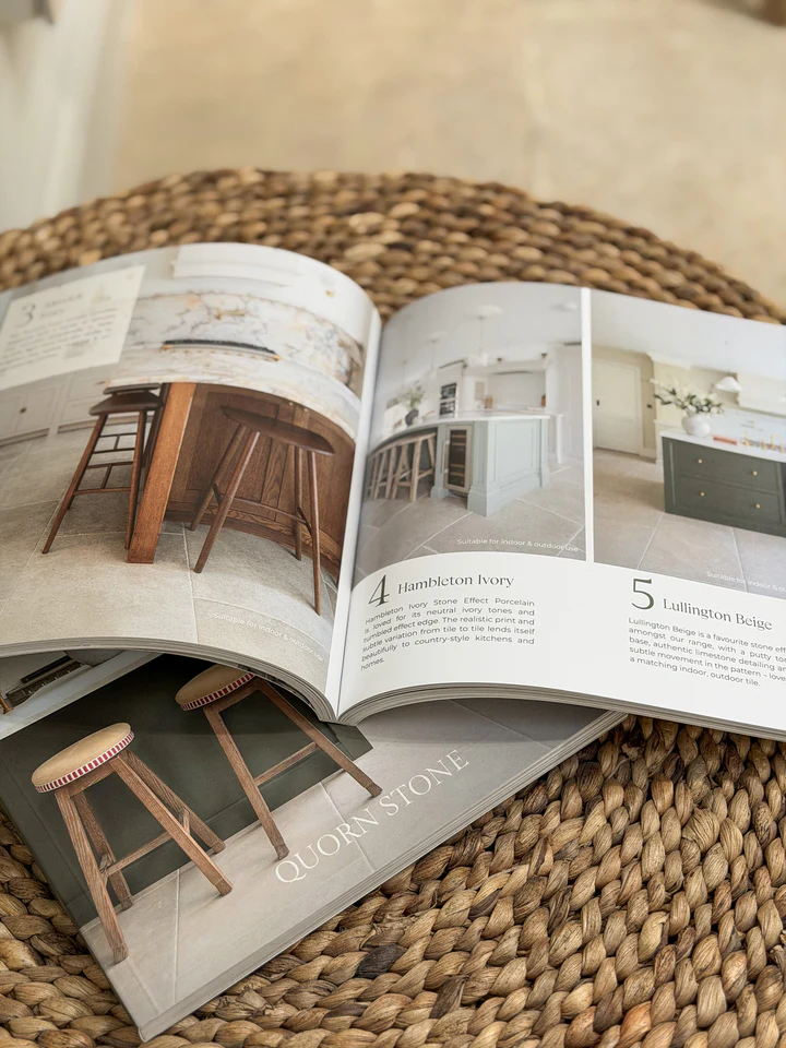 Open flooring catalog featuring Quorn Stone and Hambleton Ivory kitchen tile samples and stools on a woven seagrass placemat