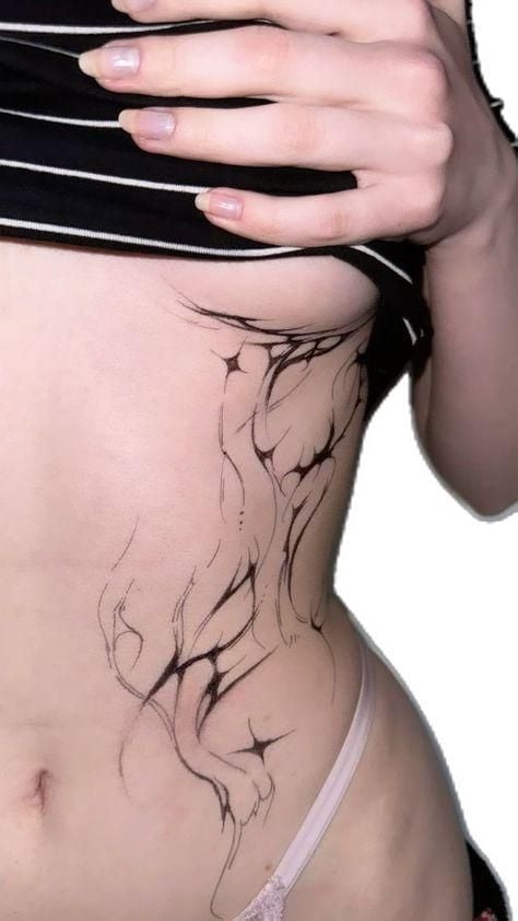 Close-up of person's rib-side abstract black linework tattoo with flowing organic shapes and star-like accents, striped top lifted to reveal.
