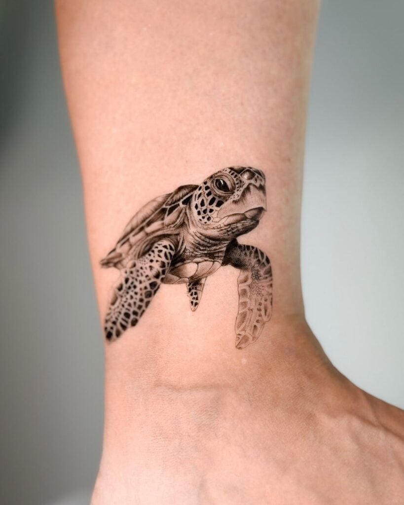 Realistic black ink sea turtle ankle tattoo with intricate dotwork and shading — small marine life tattoo on foot.