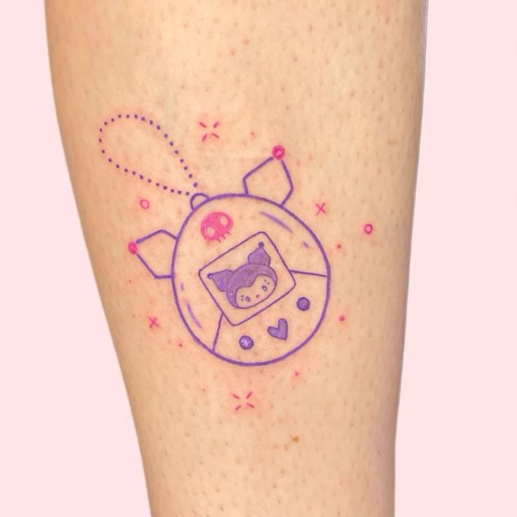 Kawaii Tamagotchi-style purple and pink keychain tattoo of a cartoon character on forearm