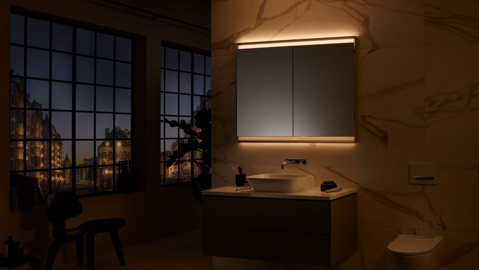 Modern marble bathroom with floating vanity, LED-lit mirror, vessel sink and nighttime cityscape visible through large industrial windows.