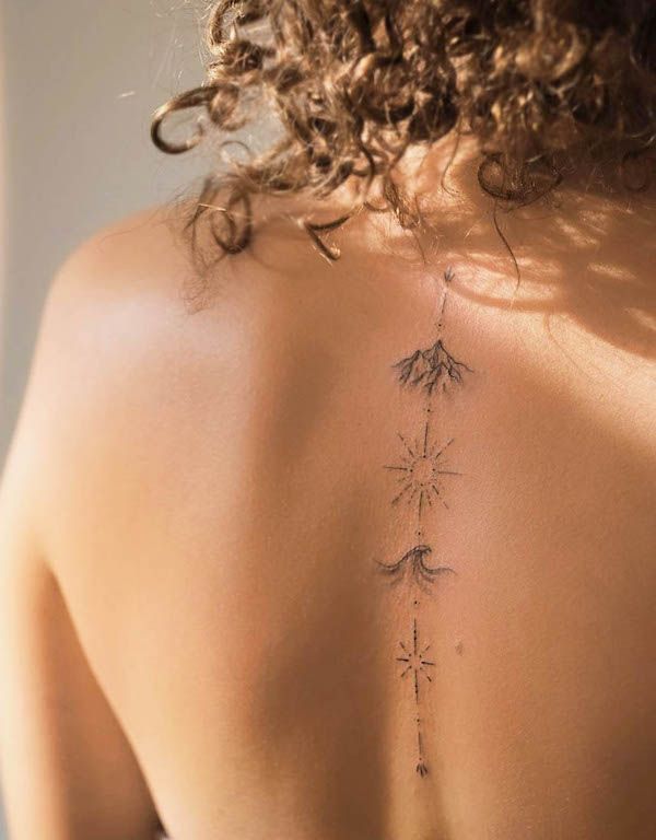 Minimalist vertical spine tattoo on a woman's upper back featuring mountain, compass/star motifs and a wave line in delicate black ink.