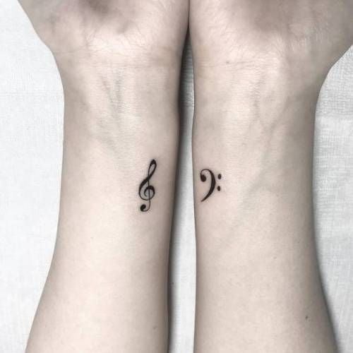 Treble and bass clef wrist tattoos on inner wrists, minimalist small black music note tattoos