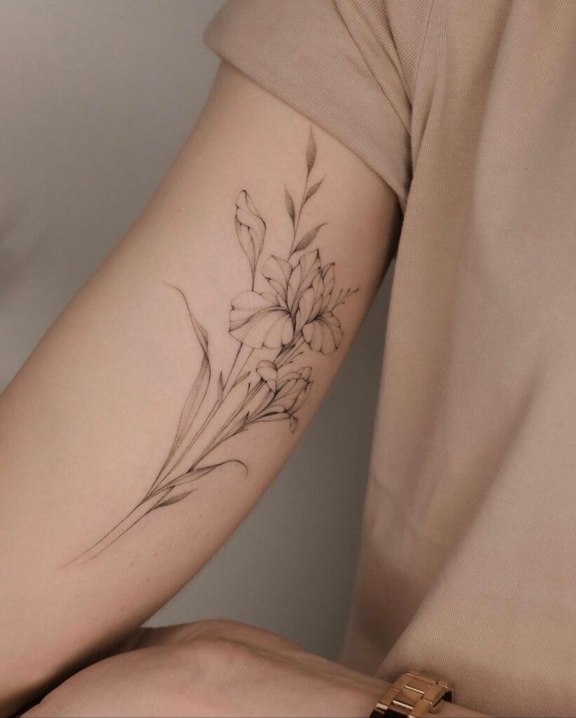 Minimal fine-line black ink floral forearm tattoo of delicate blooming flowers and leaves on inner arm