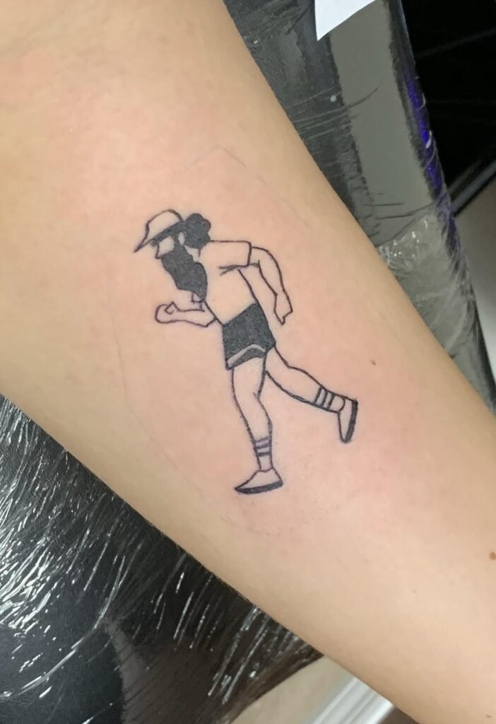 Minimalist runner tattoo: black line illustration of a bearded runner in cap, t‑shirt, shorts and striped socks on forearm