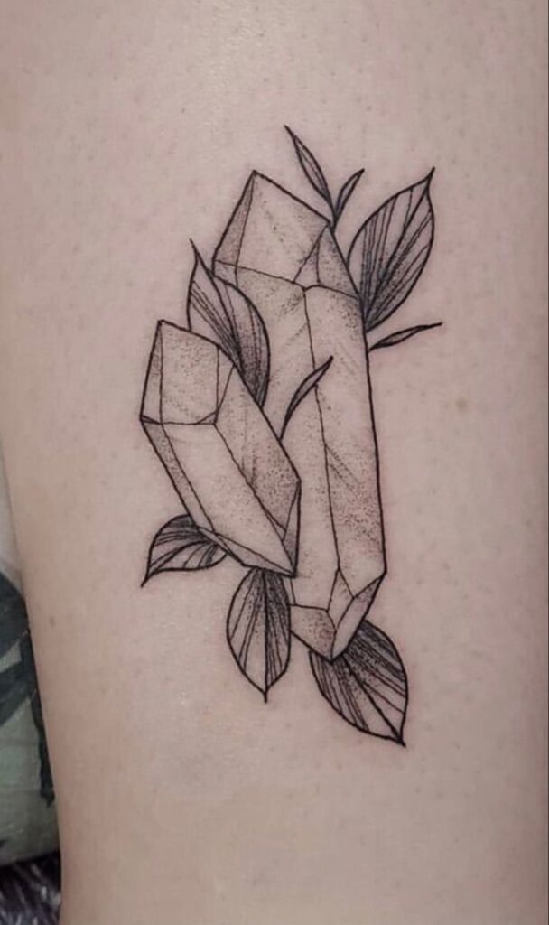 Minimal black linework crystal tattoo with botanical leaves and subtle dotwork shading