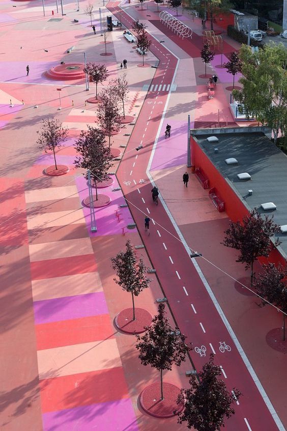 97a3f13d1caa7df570c02a6fb282f9f2 Aerial view of vibrant pink and red urban plaza with dedicated bike lane, cyclists, trees, and geometric pavement | Sky Rye Design Aerial view of vibrant pink and red urban plaza with dedicated bike lane, cyclists, trees, and geometric pavement